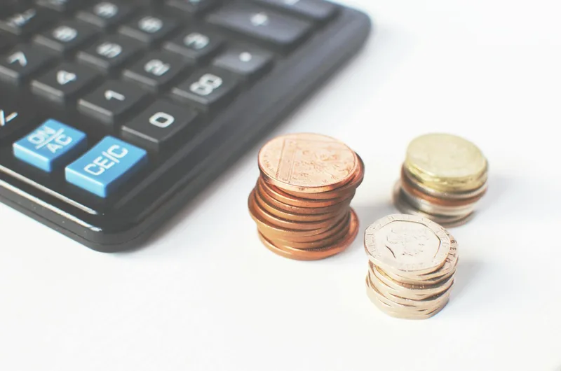 Coins and calculator representing software pricing and financial planning for ecommerce sellers in Indonesia