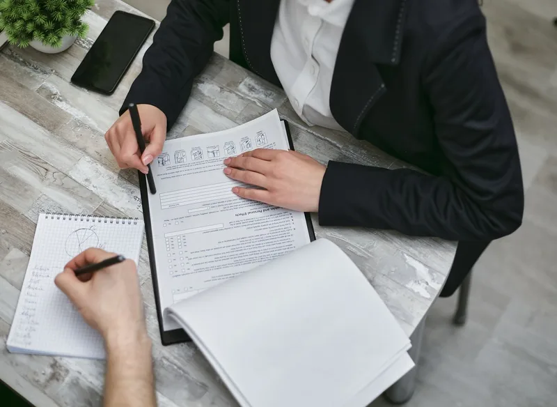 Two colleagues reviewing paperwork and taking notes for a business application