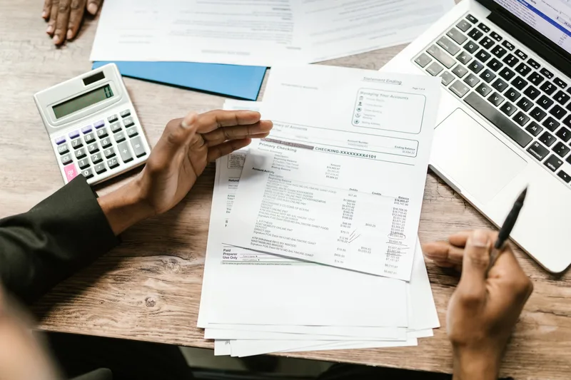 Business owner reviewing financial documents with a calculator and laptop