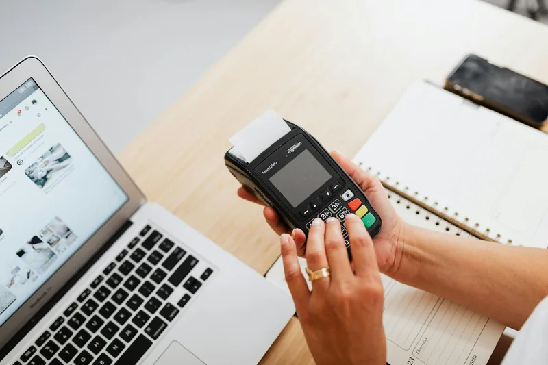 Indonesian ecommerce merchant reviewing payment analytics on computer with Shopee Seller Center dashboard showing Rupiah BNPL transaction breakdown and monthly payout summary