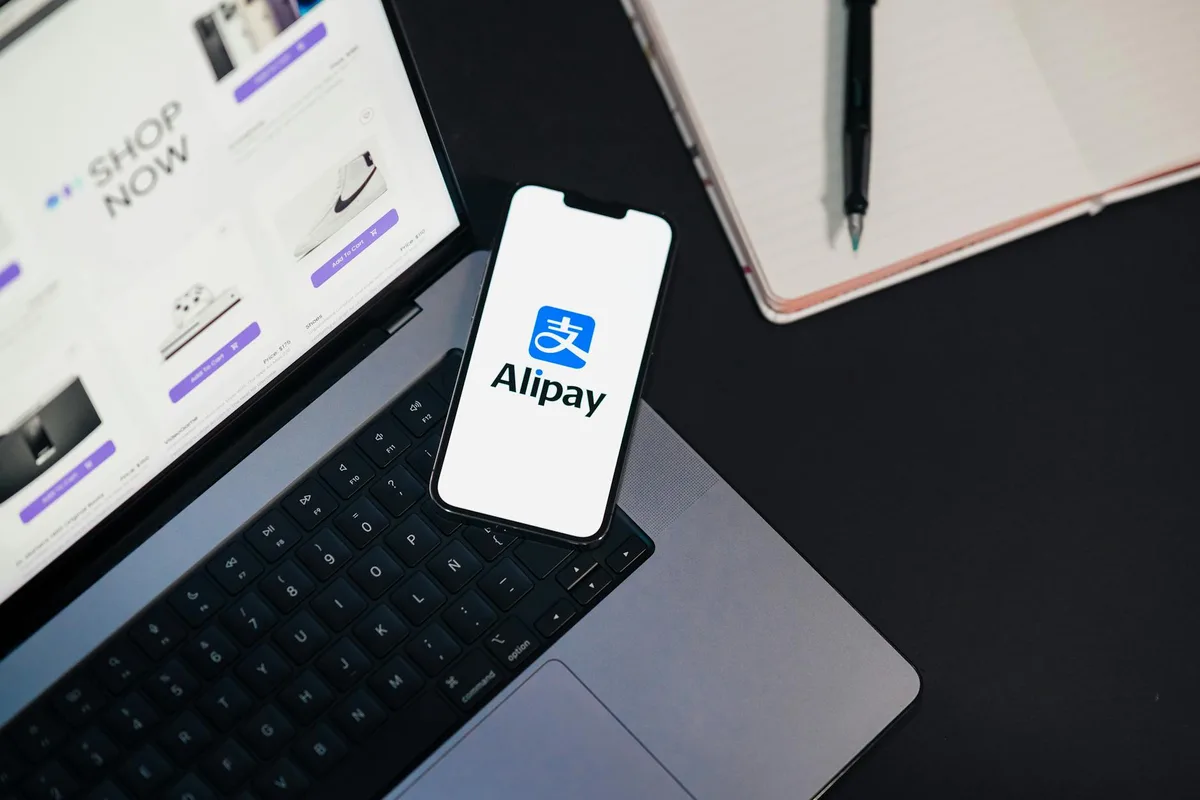 Mobile payment app on smartphone with laptop showing an online shopping checkout for ecommerce